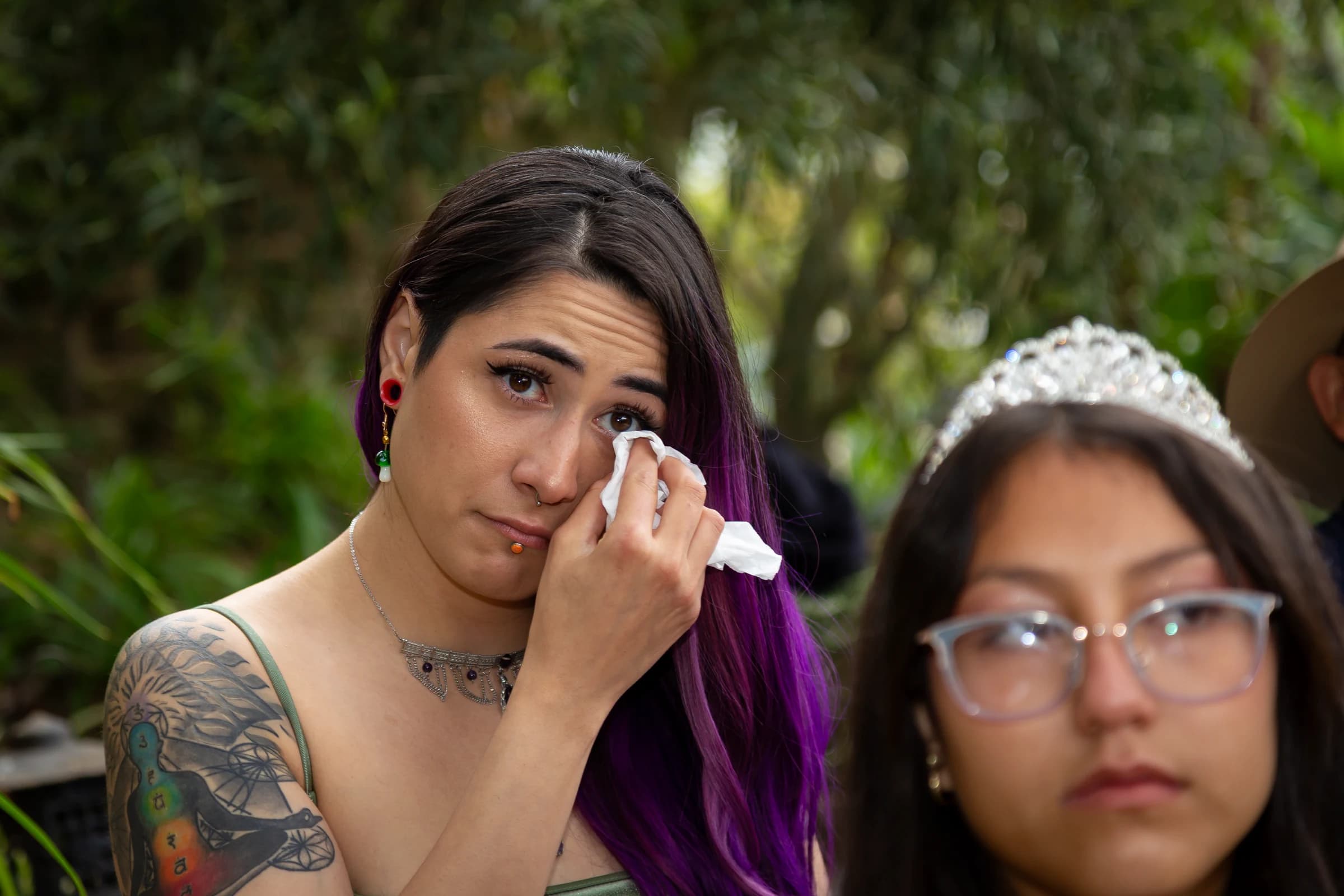 A wedding guest wipes away a tear during an outdoor ceremony