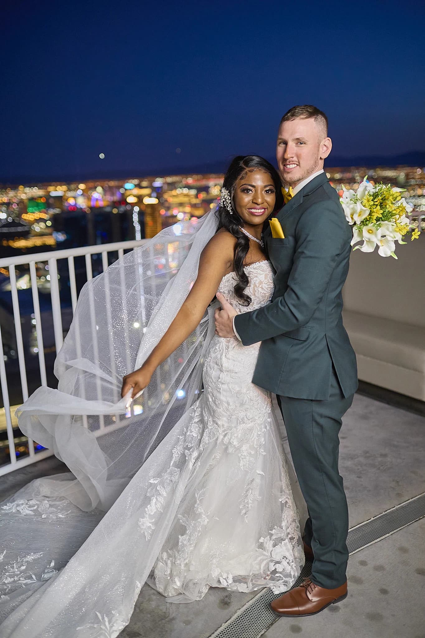 Newlyweds pose above the glowing Las Vegas skyline at night